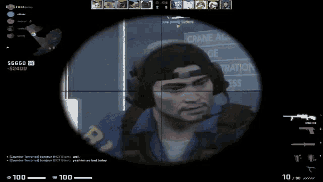 a sniper scope shows a man wearing headphones and a hat with the word crane on it
