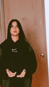 a girl wearing a black nike hoodie stands in front of a door