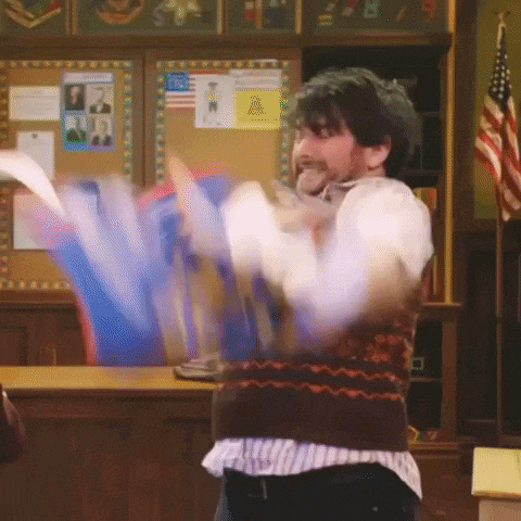 a man in a sweater is throwing papers in a classroom .