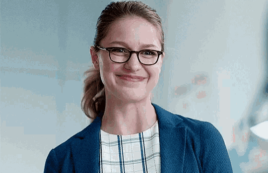 the woman is wearing glasses and a blue jacket and smiling .