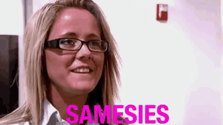a woman wearing glasses is smiling and the word samesies is in pink letters .