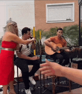 a man is playing a guitar while a woman sings into a microphone .
