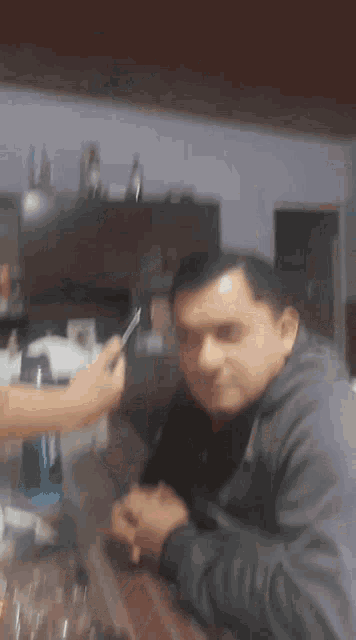 a blurry picture of a man sitting at a table with a cell phone in his hand