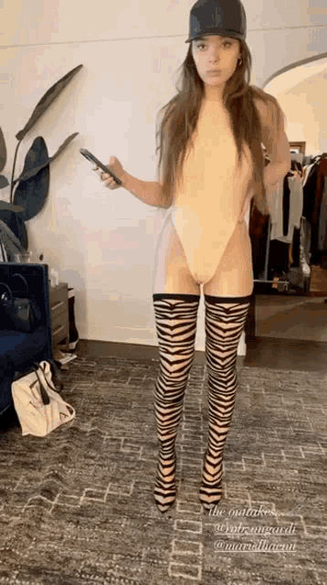 a woman wearing a swimsuit and zebra print stockings is holding a cell phone