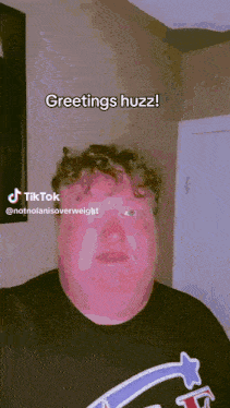 a man in a black shirt says greetings huzz on a tik tok video