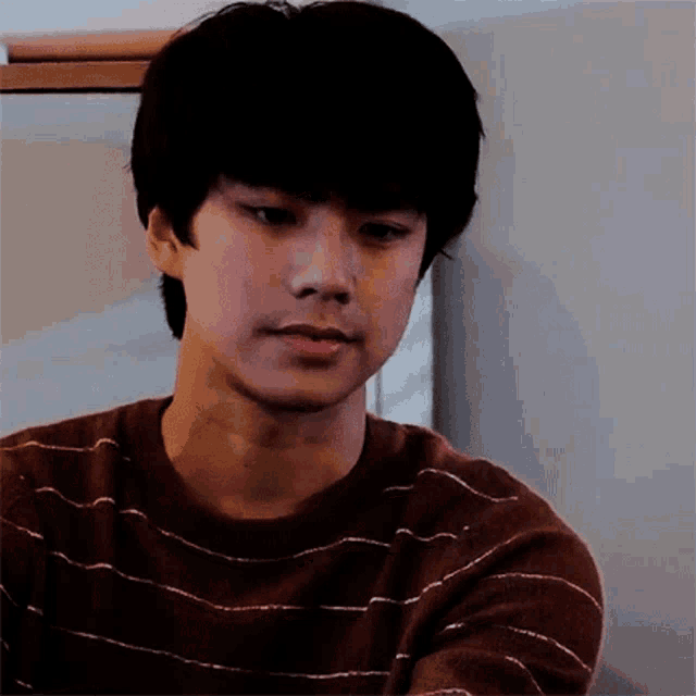 a young man wearing a striped sweater is looking at something