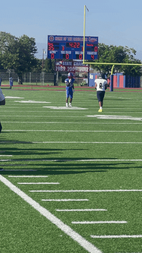 football players on a field with a scoreboard that says state champions