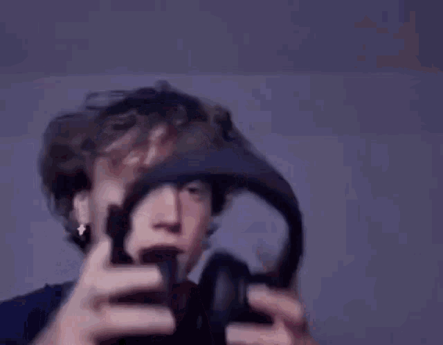 a young man is wearing headphones on his head and looking at the camera .