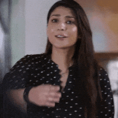 a woman in a black and white polka dot shirt is smiling and talking .