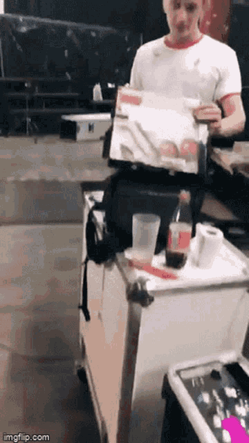 a man in a white t-shirt is holding a box with a picture on it