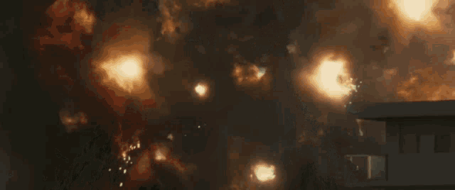 a large explosion is taking place in a dark room with a building in the background .