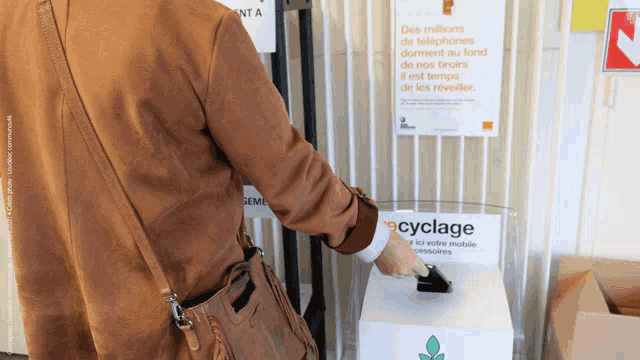 a woman is putting a watch into a recycling bin