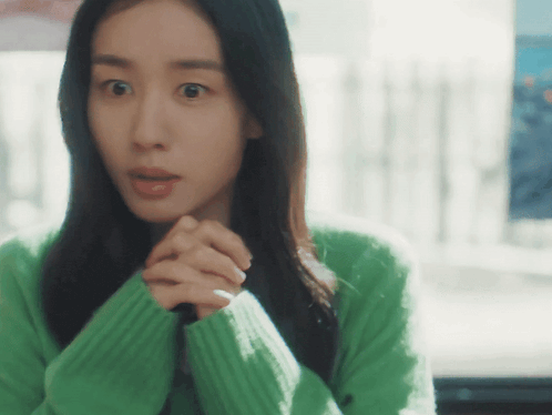 a woman in a green sweater looks at the camera