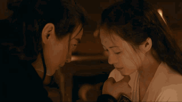 a man and a woman are looking at each other and the woman is touching the man 's face