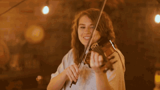 a woman is smiling while playing the violin