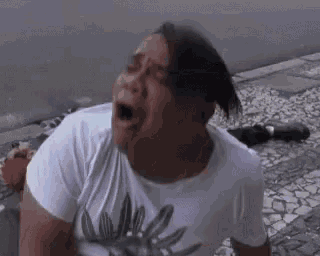 a man in a white shirt is crying on the street .