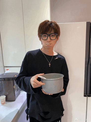a man wearing glasses and a necklace holds a pot