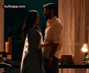 a man and a woman are standing next to each other in a room holding hands .
