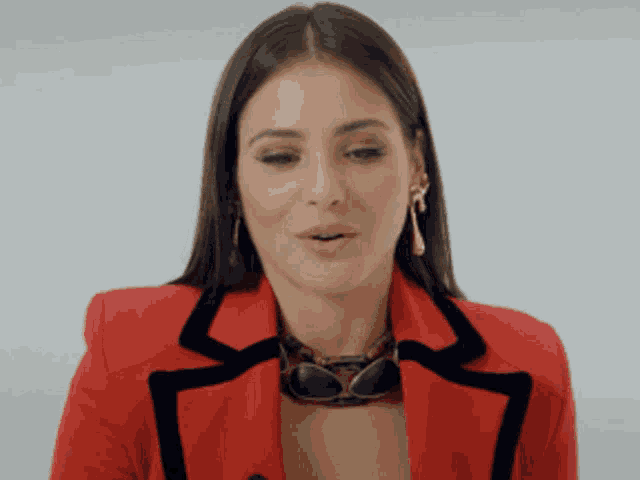 a woman wearing a red jacket and sunglasses makes a funny face