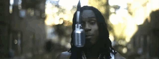 a man with dreadlocks is holding a microphone to his face .