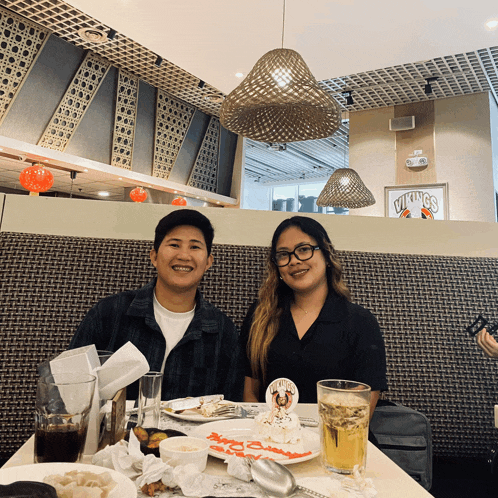 a man and a woman sit at a table with a duck king sticker on a plate
