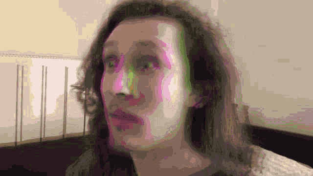 a man with long hair and a surprised look on his face .