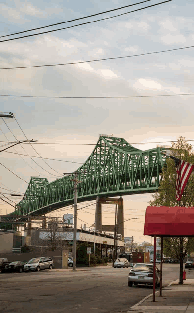 a green bridge over a city street with a red awning