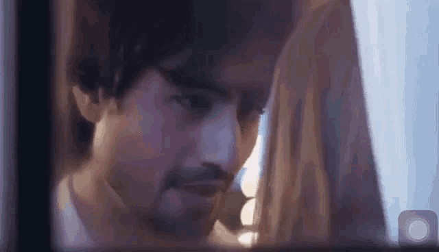 a man and a woman are looking at each other in a mirror .