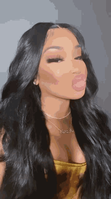 a woman with long black hair is blowing a pink bubble with her tongue .