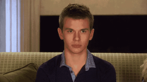 a young man is sitting on a green couch and looking at the camera