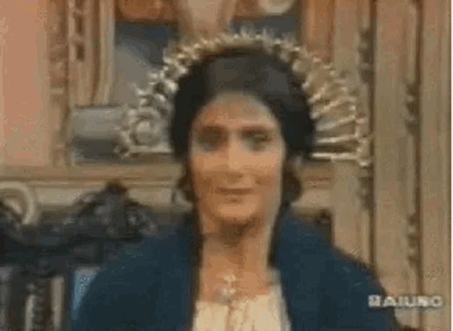 a woman wearing a crown on her head is standing in front of a painting in a room .