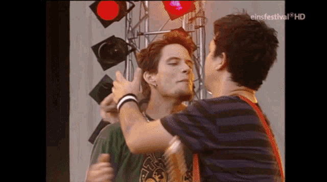 two men are kissing in front of a sign that says " einfestival hd "
