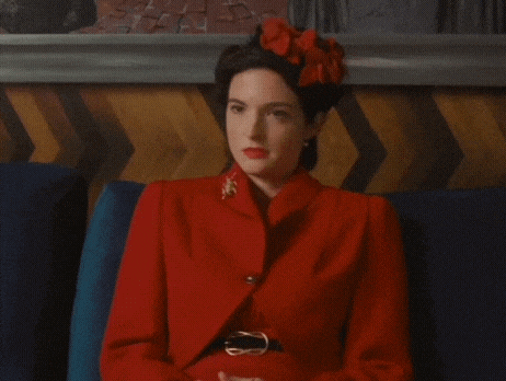 a woman in a red suit is sitting on a couch .