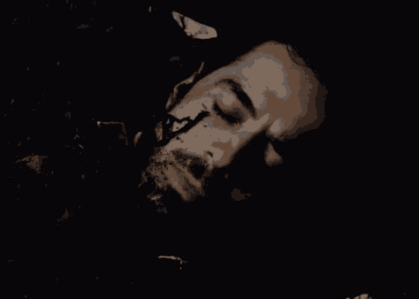 a man with a beard is laying in the dark