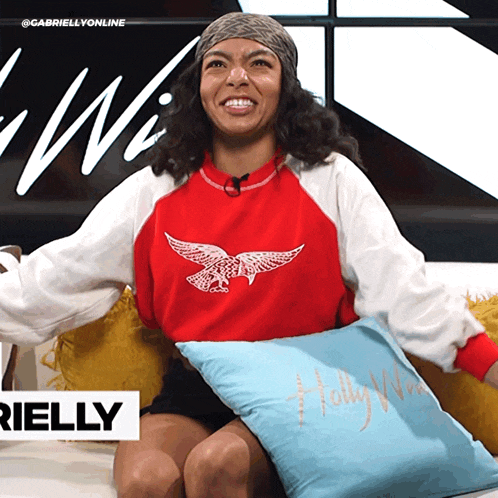 a woman is sitting on a couch with a pillow that says holly williams
