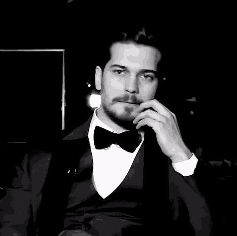 a man in a tuxedo and bow tie is sitting down
