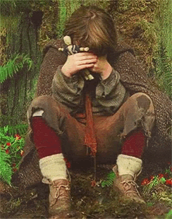 a young boy is covering his face with his hands
