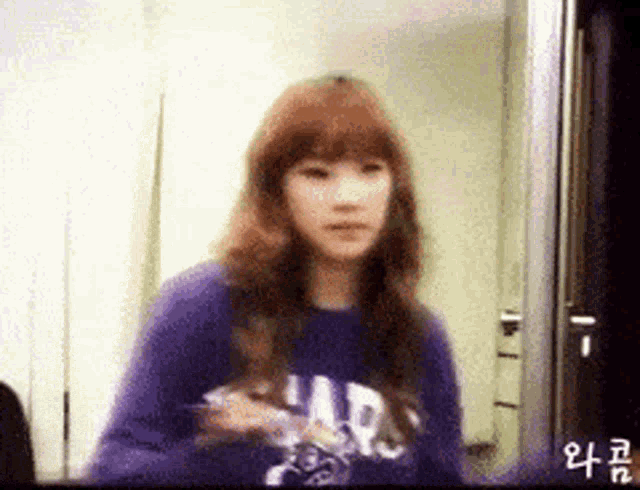 a girl wearing a purple gap sweatshirt looks at herself in the mirror