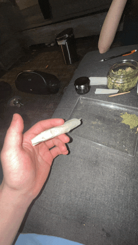 a person is holding a joint in their right hand