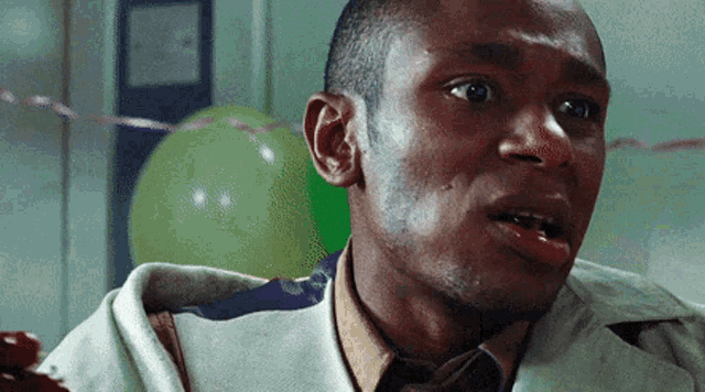 a close up of a man 's face with a green balloon in the background