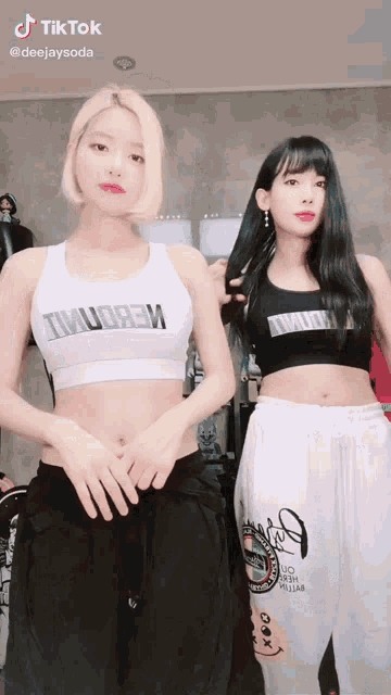 two women are standing next to each other and one of them has a crop top that says twudgem on it