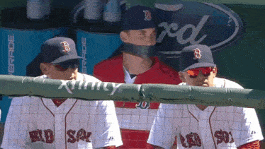 a man wearing a boston red sox hat is taped to a wall
