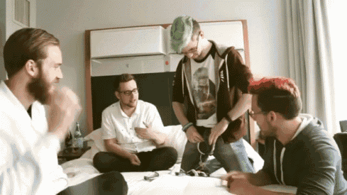 a group of men are sitting on a bed with one wearing a shirt that says ' nintendo '