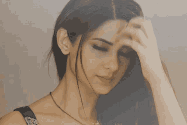 a close up of a woman 's face with a hand on her forehead