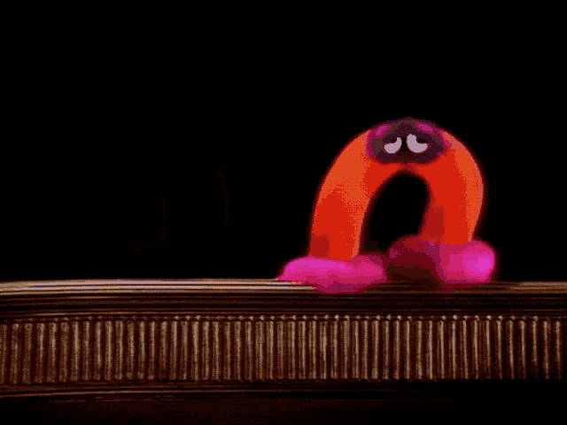a colorful worm with a pink furry head is moving on a black background