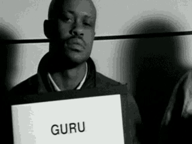 a man is holding a sign that says guru on it .