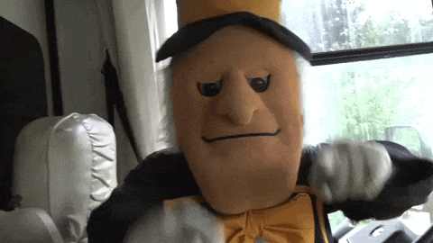 a mascot wearing a top hat and bow tie stands in front of a window