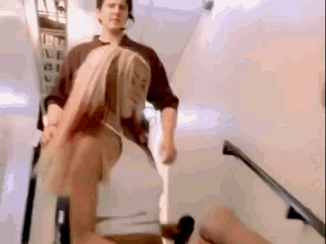 a woman is sitting on a staircase while a man holds her hand .