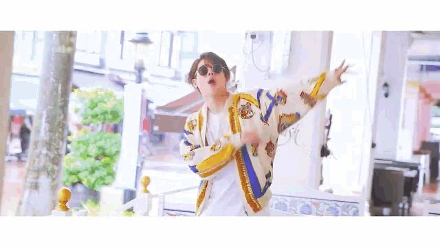 a man with his arms outstretched wearing a colorful jacket