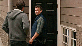 two men standing in front of a door talking